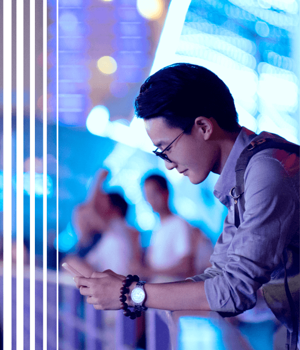 Rapaz asiático debruçado em grade mexendo no celular